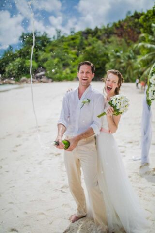 Traumhochzeit auf den Seychellen am Strand mit glücklichem Brautpaar.